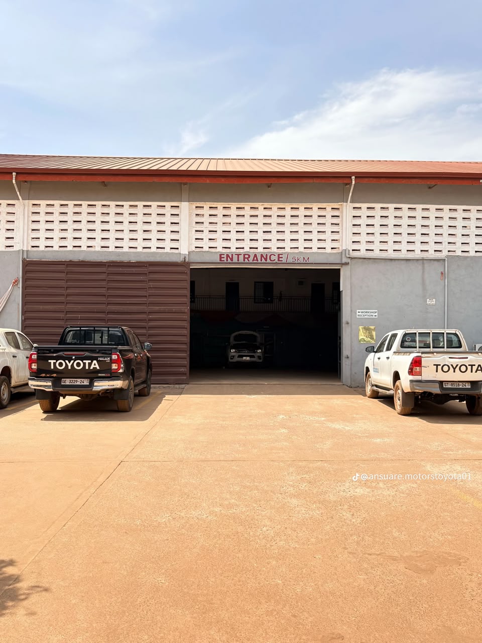 Main entrance of the Ansuare Motors workshop with Toyota Hilux pickups parked outside